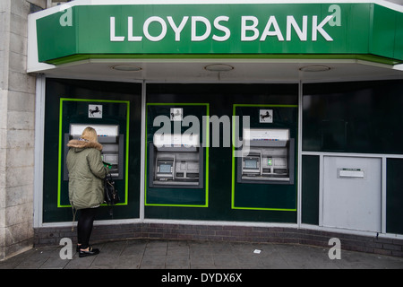 Una donna che utilizza ATM cash point macchine presso una filiale della Banca di Lloyds, Cardiff City Centre Foto Stock