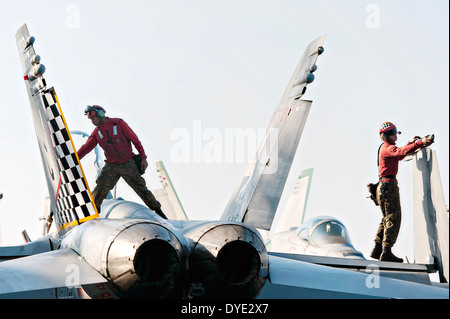 US Marine meccanica del volo di eseguire la manutenzione su di un F/A-18C Hornet sul ponte di volo della portaerei USS Harry Truman Febbraio 12, 2014 operanti nel Golfo di Oman. Foto Stock