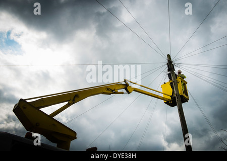 Un BT British Telecom engineer lavora in altezza da un fissaggio cherrypicker rammendo fili telefono linee sul telegrafo polo UK Foto Stock