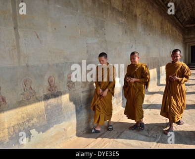 Visitando i monaci in giallo passeggiando tra il bassorilievo scene dal periodo indù nell'ingresso principale di Angkor Wat Gateway, Siem Reap, Cambogia Foto Stock