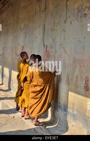 Visitando i monaci in giallo passeggiando tra il bassorilievo scene dal periodo indù nell'ingresso principale di Angkor Wat Gateway, Siem Reap, Cambogia Foto Stock