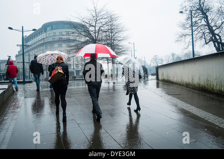 La gente camminare sotto la pioggia con ombrelloni, Cardiff City Centre 28 Marzo 2014 Foto Stock