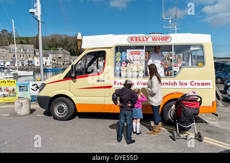 Una mamma con bambini piccoli acquisti da un tradizionale britannica Cornish ice cream van dal porto di sole a Padstow, Cornwall, Regno Unito Foto Stock