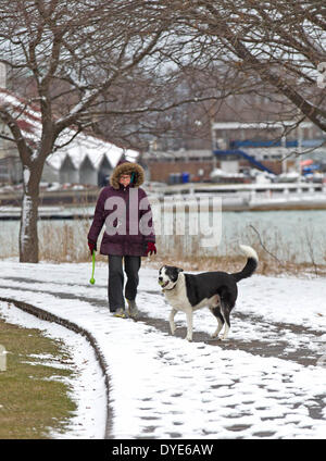 Toronto, Canada. 15 apr 2014. Una donna cammina il suo cane dal lago Ontario in Canada, a Toronto, il 15 aprile 2014. Una neve di primavera ha colpito Toronto Martedì quando la temperatura è scesa a meno 7 gradi centigradi. Credito: Zou Zheng/Xinhua/Alamy Live News Foto Stock