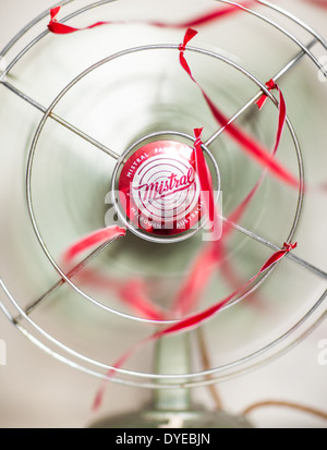 Un vecchio verde Ventilatore da tavolo con nastri di colore rosso su sfondo bianco Foto Stock