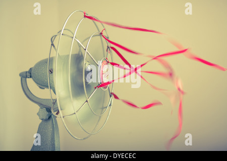 Un vecchio verde Ventilatore da tavolo con nastri di colore rosso su sfondo bianco Foto Stock