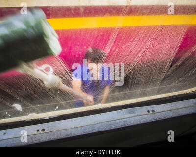 Bangkok, Tailandia. Xvi Apr, 2014. Una delle Ferrovie dello Stato della Thailandia dipendente lava i Windows su un treno passeggeri a Bangkok. Thai autostrade, treni e autobus sono stati imballati mercoledì come Thais iniziato a ritornare a casa dopo la lunga pausa Songkran. Songkran è normalmente di tre giorni lungo ma questo anno molti thailandesi avevano almeno un giorno supplementare off perché la vacanza è iniziato domenica, così molti thailandesi ha iniziato il viaggio il venerdì della scorsa settimana. Credit: Jack Kurtz/ZUMAPRESS.com/Alamy Live News Foto Stock