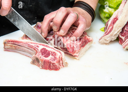 Lo chef prepara e tagli costolette di agnello Foto Stock