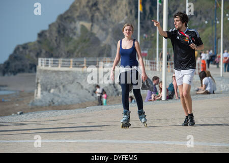 Aberystwyth, Wales, Regno Unito. Il 16 aprile 2014. Una giovane donna con i pattini godendo il sole sul lungomare a Aberystwyth all'inizio delle vacanze di Pasqua stagione. La temperatura nel Galles occidentale resort ha raggiunto le alte teens centigradi nel tardo pomeriggio. Il Meteo previsioni è di diventare cloudier e wetter nei prossimi giorni, ma riscaldando nuovamente dalla Domenica di Pasqua Photo credit: keith morris/Alamy Live News Foto Stock