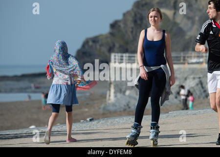 Aberystwyth, Wales, Regno Unito. Il 16 aprile 2014. Una giovane donna con i pattini godendo il sole sul lungomare a Aberystwyth all'inizio delle vacanze di Pasqua stagione. La temperatura nel Galles occidentale resort ha raggiunto le alte teens centigradi nel tardo pomeriggio. Il Meteo previsioni è di diventare cloudier e wetter nei prossimi giorni, ma riscaldando nuovamente dalla Domenica di Pasqua Photo credit: keith morris/Alamy Live News Foto Stock