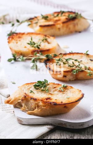 Fried crostini di pane con il timo e le foglie di spinaci su bianco tagliere.