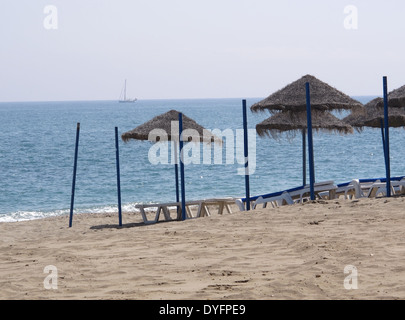 Righe di dal tetto di paglia ombrelloni su una spiaggia in Spagna Foto Stock