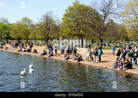 La gente seduta dal lato della serpentina in Hyde Park Londra Inghilterra Gran Bretagna REGNO UNITO Foto Stock