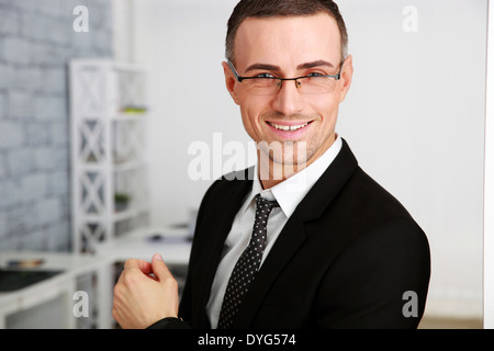 Allegro imprenditore in bicchieri in piedi in ufficio Foto Stock