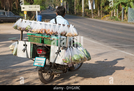 L uomo sulla moto di vendita di alimenti in sacchetti di plastica della Thailandia Foto Stock