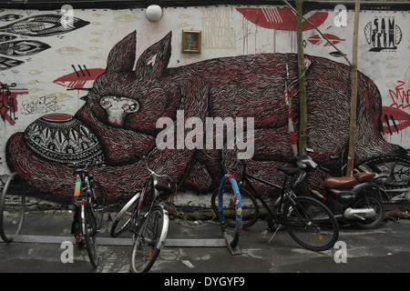 Biciclette appoggiata cerchiature metalliche decorate con la guerriglia della maglia davanti a Sam equipaggio monster murale, Rosenthaler Strasse 39, Berlino Foto Stock