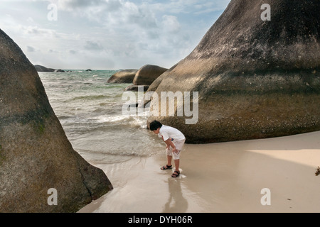 Ragazzo che guarda per i serbatoi, Tanjung Tinggi beach, Belitung Island, Indonesia Foto Stock