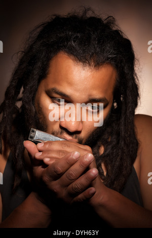 Rastafarian Man Riproduci armonica a bocca Foto Stock