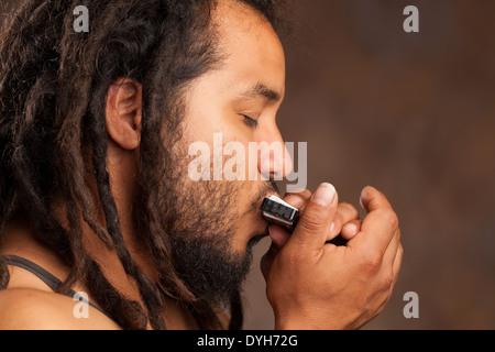 Rastafarian Man Riproduci armonica a bocca Foto Stock