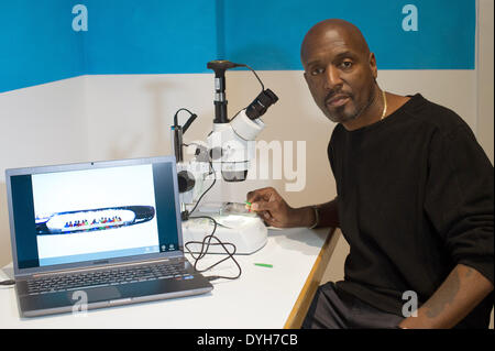 Amburgo, Germania. Xiv Apr, 2014. British microsculpture artista Willard Wigan si siede di fronte a un microscopio nella mostra "Kleine Welten" (piccoli mondi) nel Museo fuer Kunst und Gewerbe di Amburgo, Germania, 14 aprile 2014. La mostra il suo piccolo sculture apre il 14 aprile 2014 presso la MKG. Foto: MAJA HITIJ/dpa/Alamy Live News Foto Stock