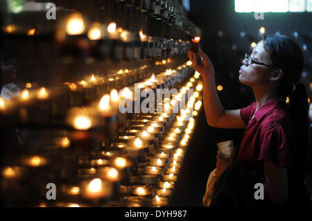 Quezon City, Filippine. Xvii Apr, 2014. QUEZON Quezon City, Filippine - Una donna accende una candela dopo aver preso parte alle Stazioni della Croce all'interno di una cappella in Quezon City, a nord-est di Manila il Giovedì Santo, 17 aprile 2014. Molti devoti contrassegnare la Settimana Santa da sottoposto a diverse forme di penitenza fisica nella convinzione che questi si esime dai loro peccati. Credito: George Calvelo/NurPhoto/ZUMAPRESS.com/Alamy Live News Foto Stock