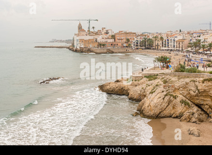 Belle spiagge di Sitges sullo sfondo la chiesa di Sant Bartomeu & Santa Tecla. Le persone godono di acqua in una giornata di sole Foto Stock