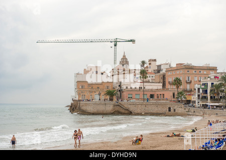 Belle spiagge di Sitges sullo sfondo la chiesa di Sant Bartomeu & Santa Tecla. Le persone godono di acqua in una giornata di sole Foto Stock