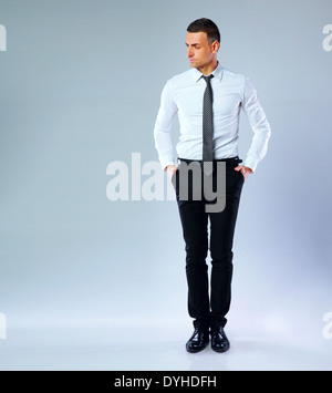 Ritratto a figura intera di pensieroso imprenditore su sfondo grigio Foto Stock