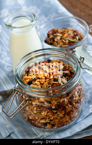 Muesli fatti in casa in aprire il vasetto di vetro e latte o yogurt sulla tavola con biancheria Foto Stock