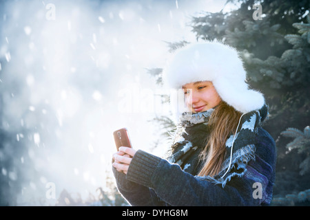 Ritratto di ragazza adolescente tenendo il telefono cellulare al di fuori in inverno Foto Stock