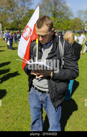 Dublino, Irlanda. Il 18 aprile 2014. Un pellegrino polacco porta una bandiera polacca. L Arcivescovo di Dublino Diarmuid Martin, ha portato a diverse centinaia di pellegrini in corrispondenzà di alcune stazioni della croce' processione attraverso il Parco Phoenix e. Le stazioni con letture e canti e la meditazione dovrebbe ricordarci la passione e la crocifissione di Gesù Cristo. Credito: Michael Debets/Alamy Live News Foto Stock