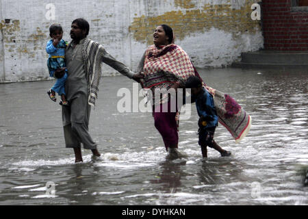 Lahore, Pakistan. Xviii Apr, 2014. Una famiglia a piedi in una strada allagata durante forti piogge in Pakistan orientale di Lahore, il 18 aprile 2014. Almeno due persone sono state uccise e molti altri feriti in pioggia incidenti correlati nella provincia pakistana del Punjab il venerdì i media locali hanno riferito. Credito: Jamil Ahmed/Xinhua/Alamy Live News Foto Stock