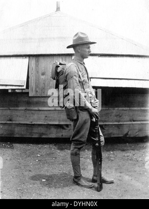 Questa fotografia tratta dalla collezione speciale Leonhardt, AD ESEMPIO, raffigura un uomo con un profilo laterale, che indossa un cappello e porta un zaino e un fucile. Si erge di fronte a un edificio rotondo in legno, evocando una scena storica. L'immagine mette in evidenza l'abbigliamento e le attrezzature tipiche di un particolare periodo di tempo, anche se non si conosce un ulteriore contesto. Foto Stock