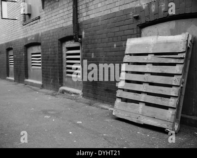 Immagine monocromatica - strada urbana scena mostrando alley con pallet in legno e porte di ventilazione, Newcastle upon Tyne, England, Regno Unito Foto Stock