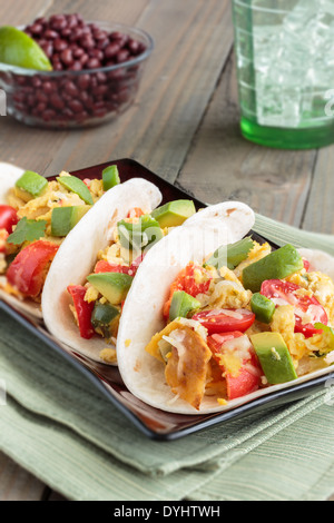 Tacos riempito con migas, Tex-Mex un piatto di uova strapazzate con peperone rosso, cipolle, jalapenos, formaggio, guarnita con avocado Foto Stock