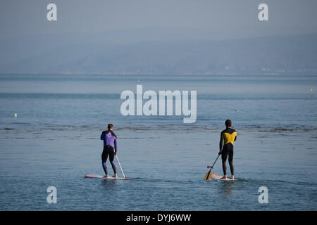 Aberystwyth, Wales, Regno Unito. Il 19 aprile 2014. Due uomini a paddle boards godere il caldo clima soleggiato all inizio del sabato di Pasqua 2014, sguazzare in calma piatta mare di Cardigan Bay off la spiaggia a Aberystwyth sulla West Wales coast. Photo credit: keith morris/Alamy Live News Foto Stock