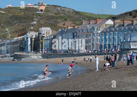 Aberystwyth, Wales, Regno Unito. Il 19 aprile 2014. Le persone che si godono il caldo sole primaverile sul Sabato di Pasqua al mare a Aberystwyth sulla West Wales coast, UK dopo una partenza a freddo, le temperature hanno raggiunto un picco a 13ºC nel pomeriggio. Il Meteo previsioni è di diventare più coperto nei seguenti giorni Photo credit: keith morris/Alamy Live News Foto Stock