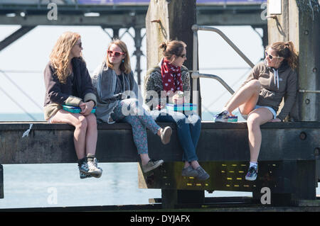 Aberystwyth, Wales, Regno Unito. Il 19 aprile 2014. Quattro giovani donne godersi il caldo sole primaverile sul Sabato di Pasqua al mare a Aberystwyth sulla West Wales coast, UK dopo una partenza a freddo, le temperature hanno raggiunto un picco a 13ºC nel pomeriggio. Il Meteo previsioni è di diventare più coperto nei seguenti giorni Photo credit: keith morris/Alamy Live News Foto Stock