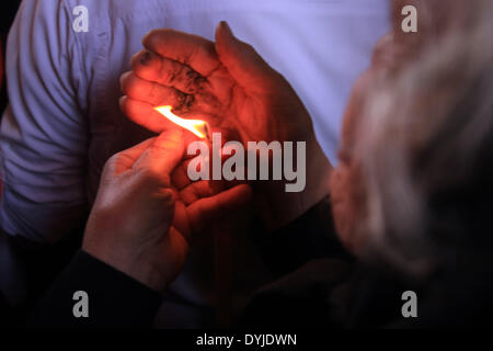 Gerusalemme, Gerusalemme, Territorio palestinese. Xix Apr, 2014. Un adoratore trattiene le candele come lei prende parte al cristiano ortodosso fuoco santo cerimonia presso la chiesa del Santo Sepolcro di Gerusalemme la città vecchia di Aprile 19, 2014. ''Fuoco santo'' è stata fatta passare tra i fedeli al di fuori della Chiesa e quindi portati alla Chiesa della Natività in Cisgiordania città di Betlemme, dove la tradizione vuole che Gesù era nato e da lì ad altre comunità cristiane in Israele e la Cisgiordania Credito: Saeed Qaq APA/images/ZUMAPRESS.com/Alamy Live News Foto Stock