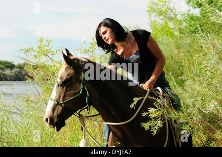 Ragazza sul suo cavallo lungo il fiume. Foto Stock