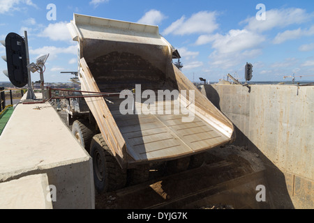 Un massiccio Hitatchi/ Diesel elettrica ibrida carrello minerario rock di dumping in un frantoio in una miniera a cielo aperto. Foto Stock