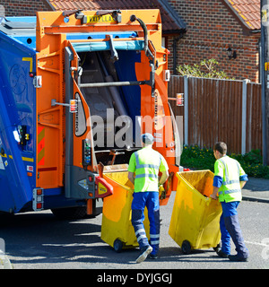 Dustmen lavora al retro del consiglio dustcart circa al posto degli scomparti di wheelie sul sollevatore idraulico per il ribaltamento in autocarro Foto Stock