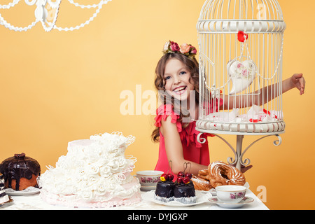 Merry ragazza in posa con dolci in interni vintage Foto Stock