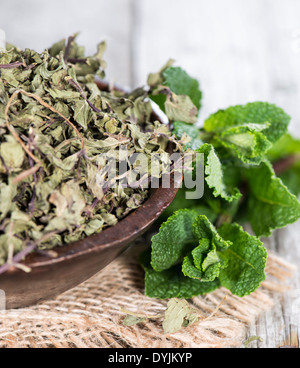 Ciotola con menta secca su vintage sfondo di legno Foto Stock