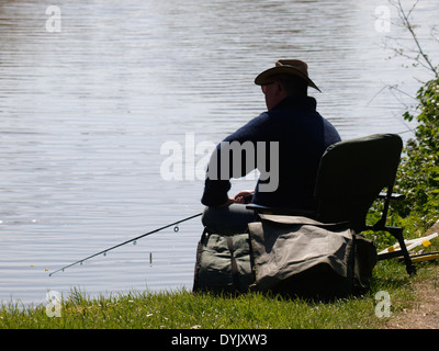 Uomo seduto pesca sulle rive di un fiume, REGNO UNITO Foto Stock