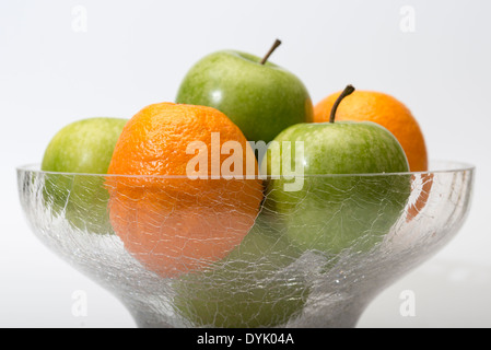 Mele e arance in recipiente di vetro, alta chiave su sfondo bianco con copia spazio. Foto Stock