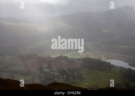 Nuvole temporalesche passando sopra Loughrigg cadde illuminato da alberi di luce del sole tra Ambleside e Grasmere Cumbria Inghilterra England Foto Stock