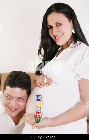 Donna incinta con il papà tenendo una lettera dai cubi - Dylan - vicino al suo ventre nel soggiorno Foto Stock