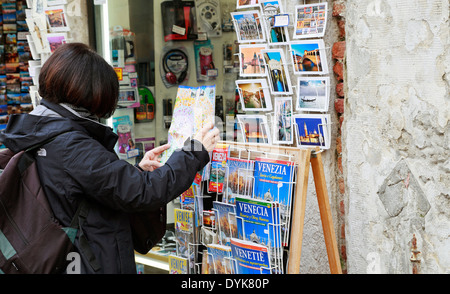 Venezia, Italia. Donna turistici Mappa di lettura al negozio di souvenir. Foto Stock