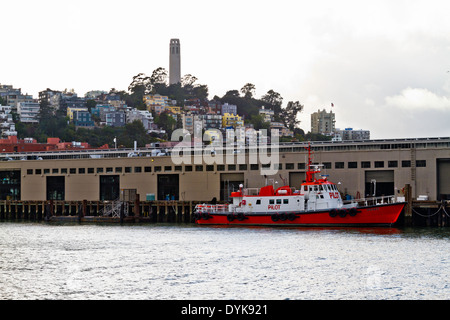 Un pilota di barca è ormeggiata in un dock nella Baia di San Francisco con una vista della Torre Coit in background con un nuvoloso, cupo cielo. Foto Stock